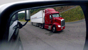 Tractor trailer seen in the side mirror of a pickup truck.